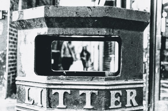 a black and white shot taken through the opening of a littler bin framing a couple walking through
